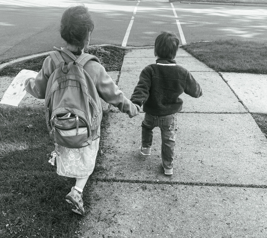 girl and boy walking down sidewalk, holding hands